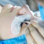 a woman getting her eyelashes done by a professional makeup artist